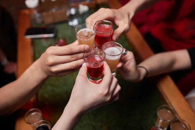 Vieren met glazen alcohol in handen gelukkige vrouwelijke vrienden die plezier hebben