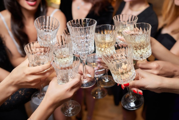 Vieren met glazen alcohol in handen gelukkige vrouwelijke vrienden die plezier hebben