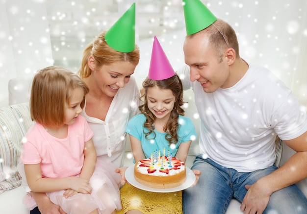 viering, familie, vakantie en mensenconcept - gelukkig gezin met twee kinderen in feestmutsen thuis