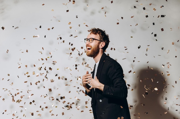 Viering Portret van een gelukkige kerel die danst onder glinsterende confetti