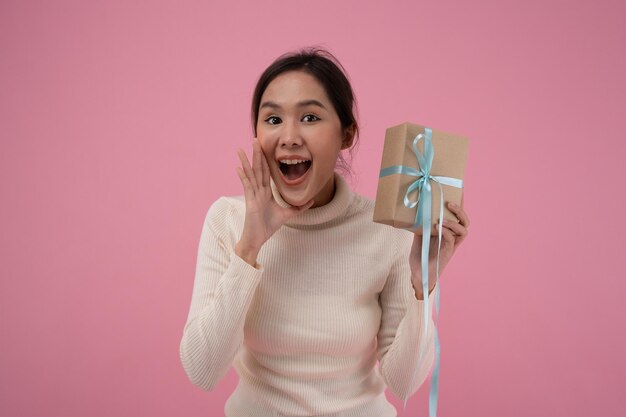 Viering vakantie presenteert jonge aziatische vrouw blij en glimlach houdt geschenkdozen vast in feest voor het vieren van verjaardag op roze achtergrond Geniet van vrouw ontvangt nieuwjaarscadeau kerstdag valentijnsdag
