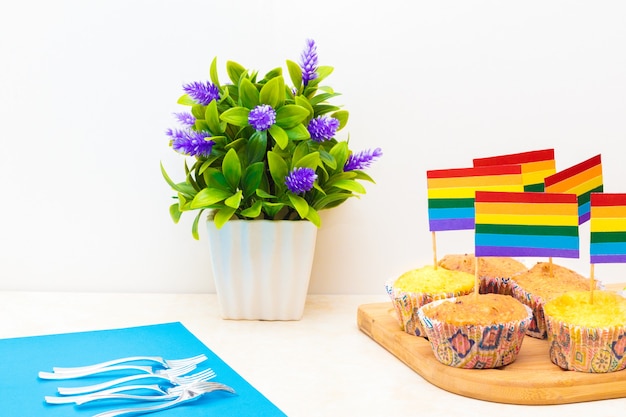 Viering van trotsdag met vlaggen op cupcakes, met een bloem in een pot op witte achtergrond on