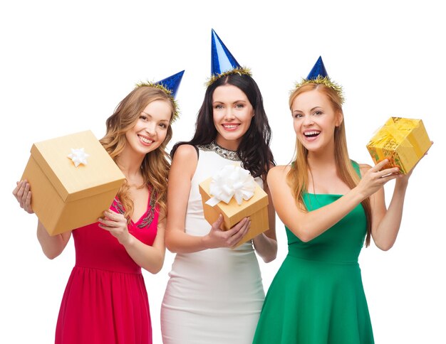 viering, vrienden, vrijgezellenfeest, verjaardagsconcept - drie glimlachende vrouwen die blauwe hoeden dragen met geschenkdozen