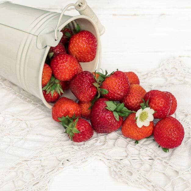 Vierkant. aardbeien op een witte houten oude achtergrond, gebreide servet