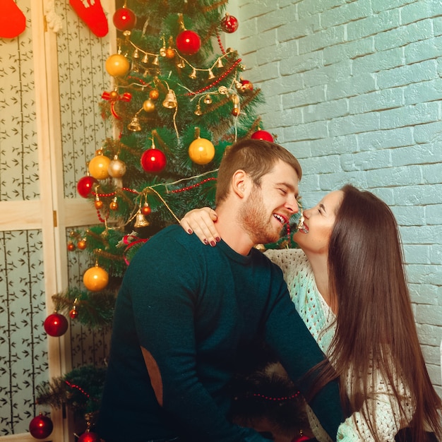 Vierkant portret van mooi paar in de buurt van kerstboom. Nieuwjaar. Kerststemming.