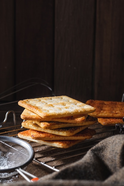 Vierkante droge crackers koekje op een houten tafel houten textuur donkere achtergrond Snack droge koekjes