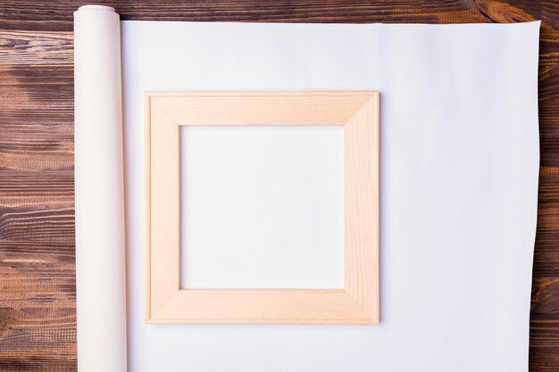 Vierkante houten brancard op een opgerolde rol van natuurlijk canvas voor het afdrukken van foto's bovenaanzicht