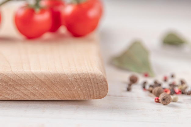 Vierkante houten snijplank met cherrytomaatjes, kaas en kruiden op een witte achtergrond met kopieerruimte voor de close-up van het tekstzijaanzicht