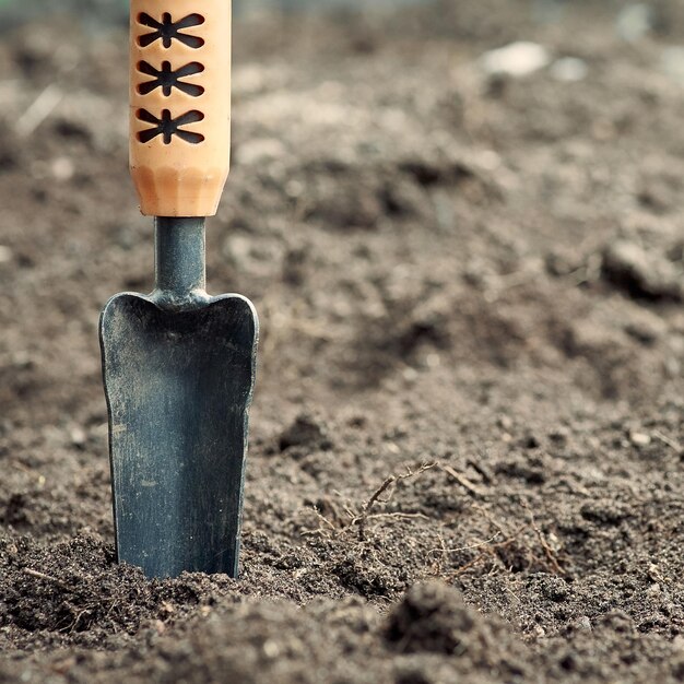 Foto vierkante opname van gebruikte vuile metalen tuin trowel op de grond