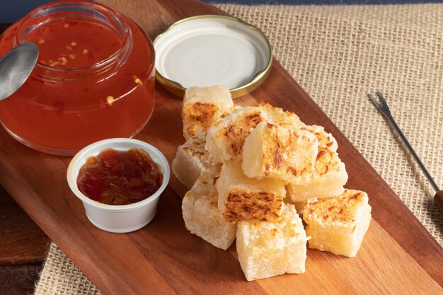 Vierkanten van tapioca (dadinho de tapioca) geserveerd met pepergelei op snijplank.