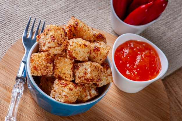 Vierkanten van tapioca en kaas geserveerd met pepergelei. Houten tafel.