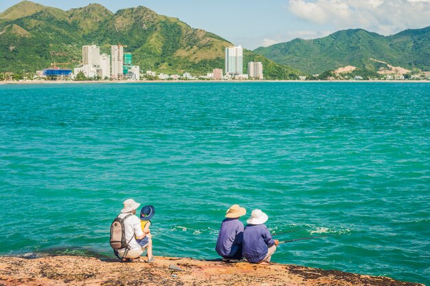 Vietnamese fishermen sitting on the edge of a cliff and fishing.