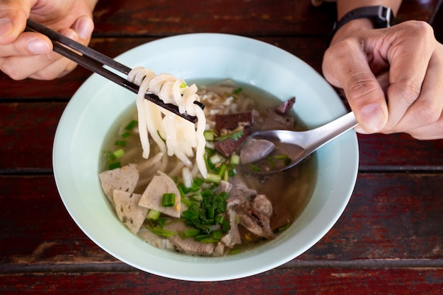 Vietnamese food Rice noodles Pho Bo vietnamese Soup with beef and chopsticks in male hand at restaurant of thailand