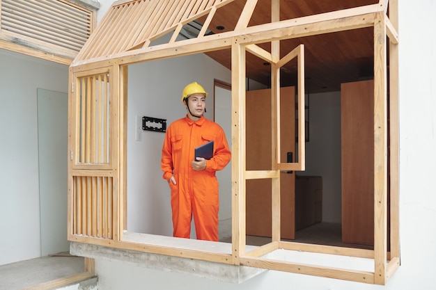 Vietnamese foreman in overall and hardhat checking house rennovation progress