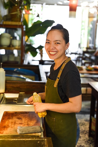 Vietnamese gelukkige serveerster die in een keuken van een café werkt