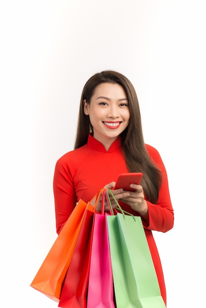 Vietnamese girl in dress traditional ao dai using smartphone to shopping online for Lunar new year