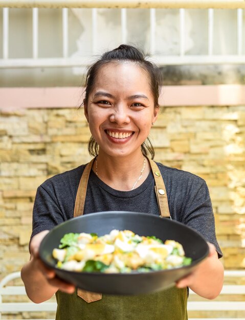 Foto cameriera felice vietnamita che mangia insalata caesar