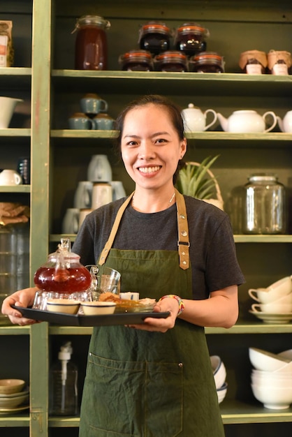 Vietnamese jonge vrouw die thee serveert in een coffeeshop