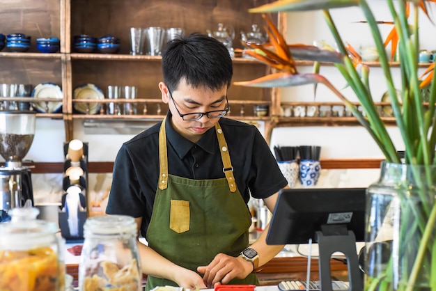 Vietnamese kelner die in toonbank met kassamachine werkt in een café