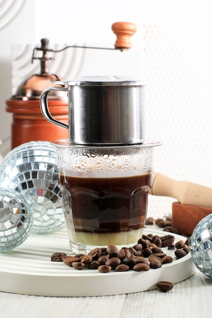 Vietnamese koffie met gecondenseerde melk in glazen bekers en traditioneel metalen koffiezetapparaat Phin. Traditionele methode voor het maken van Vietnamese koffiedruppels.