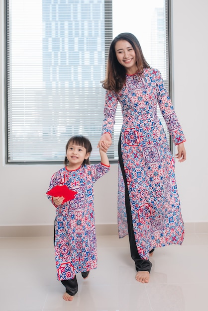 アオザイの伝統的な衣装を着たベトナム人の母と娘は、家で新年を祝います。テトホリデー。