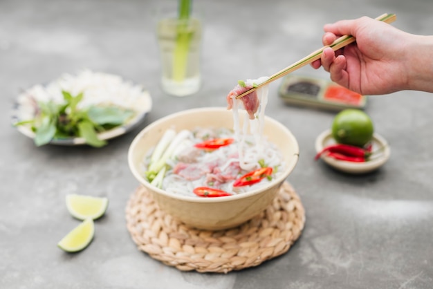 Vietnamese Pho Noedelsoep. Rundvlees met chili, basilicum, rijstnoedels, bonenscheuten met noedels die zijn opgehaald met stokjes