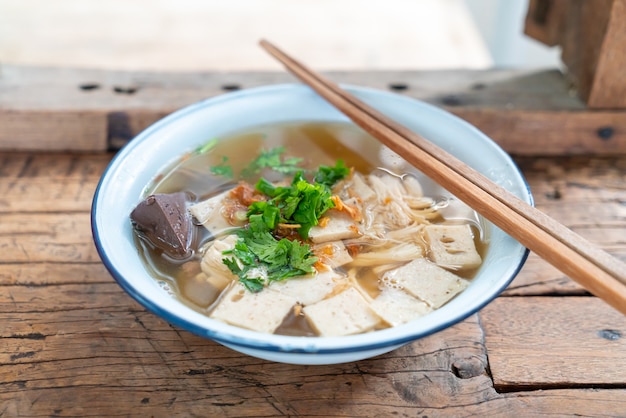 Vietnamese rijstnoedelsoep met varkensvlees en kip op houten lijst