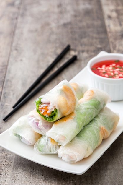 Vietnamese rolls with vegetables, rice noodles and prawns with sweet chili sauce on wooden 