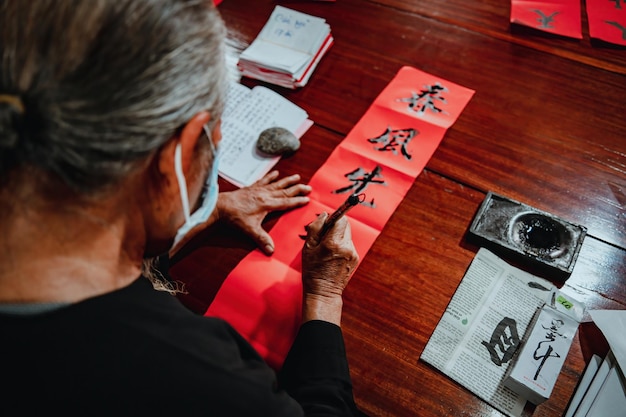 Photo vietnamese scholar writes calligraphy at long son calligraphy festival is a popular tradition during tet holiday writing couplets for spring festival new year