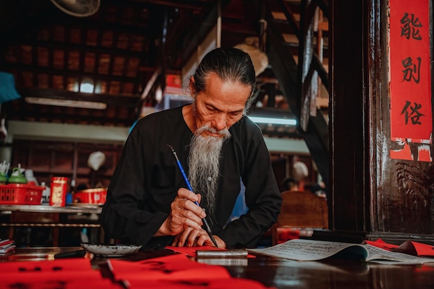 vietnamese scholar writes calligraphy at long son calligraphy festival is a popular tradition during tet holiday writing couplets for spring festival new year