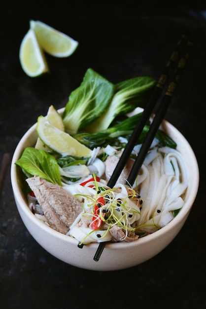 Vietnamese soep Pho Bo met groenten en rijstnoedels in een kom