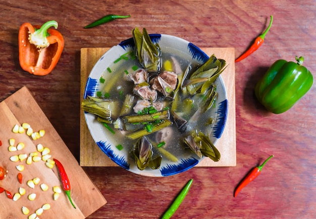 Vietnamese soup with fish and artichoke on wooden table