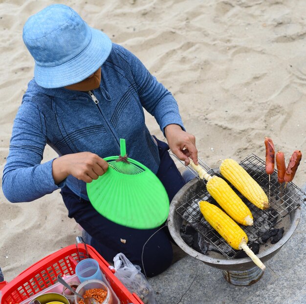 Vietnamese vrouw kookt gegrilde maïs op het strand van Nha Trang