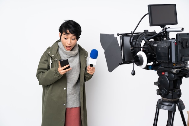 Vietnamese vrouwelijke verslaggever die een microfoon houdt en verrast nieuws meldt en een bericht verzendt
