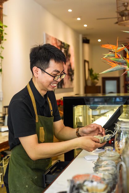 Vietnamese waiter working in counter with cashier machine in a cafe