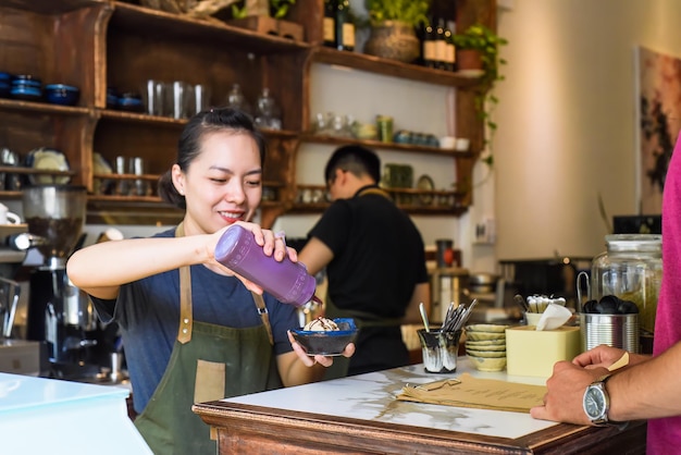 Vietnamese waitress serving ice cream for a customer in a coffee shop