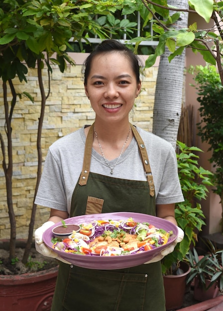 Vietnamese woman waitress serving pan fried chicken with vegetables in outdoor cafe