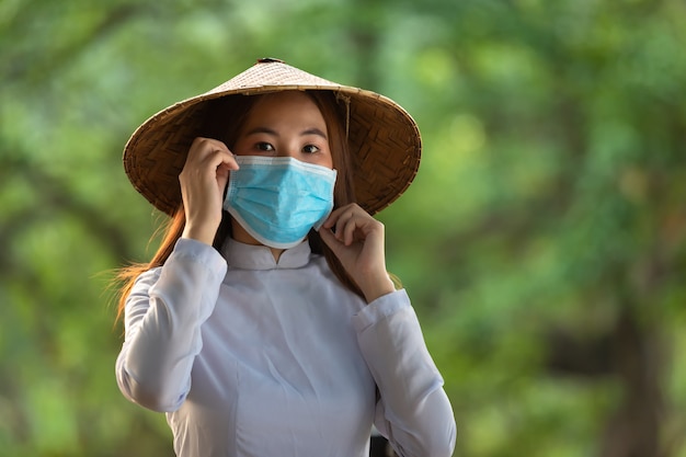 Вьетнамские женщины носят маски, Ao dai - известные традиционные маски для костюмов, концепция предотвращает распространение концепции Covid-19 Coronavirus