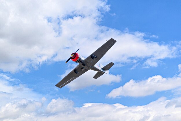 View of an aerobatic plane aerodyne in flight under a blue sky with white clouds flight exhibit