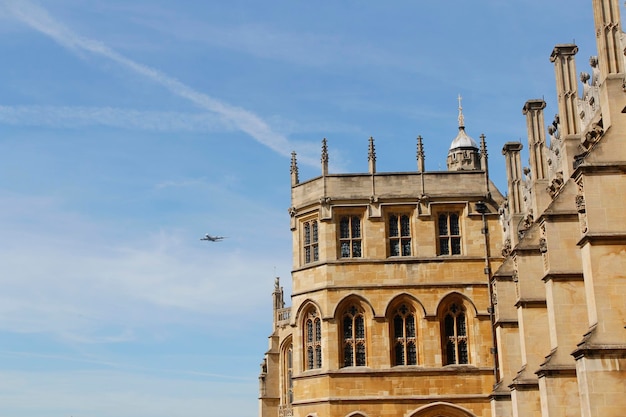 Photo view of an aeroplane on sky with the st georges chapel in windsor castle on a sunny day