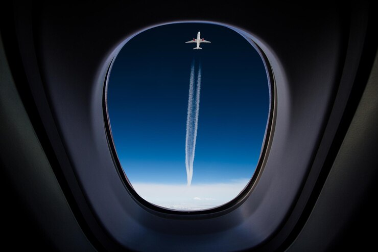 Photo view of airplane flying against clear blue sky seen through window