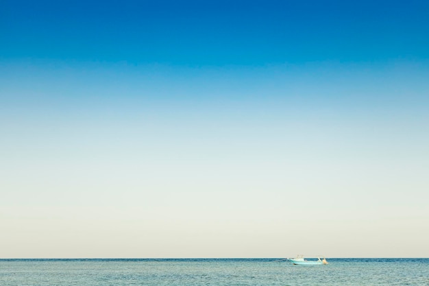 Вид на одинокую синюю лодку или корабельную яхту в тихой морской или океанской воде