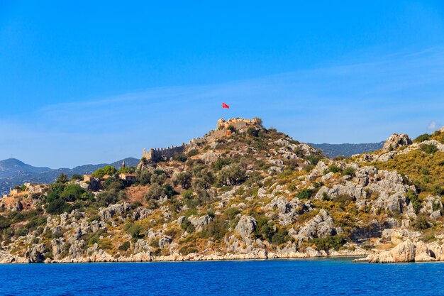 View of ancient Lycian town Simena with fortress on a mount on the coast of the Mediterranean sea in Antalya Province Turkey