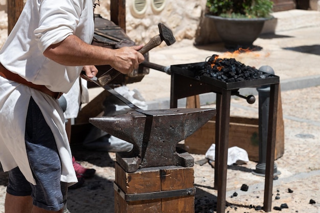 View of an artisan blacksmith working in the forge with the anvil and hammer