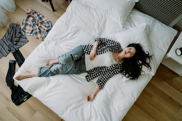 Above view of asian female lying in bed feeling depressed, lack\
of motivation to do anything. korean unemployed woman staying in\
bed with low spirit, wasting her life doing nothing.