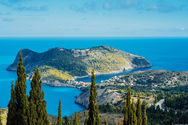 Above view to Assos village and beautiful blue sea Cypress trees stands out in foreground Kefalonia