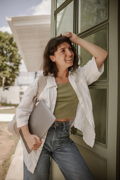 Foto vista del computer portatile sorridente attraente della tenuta della donna