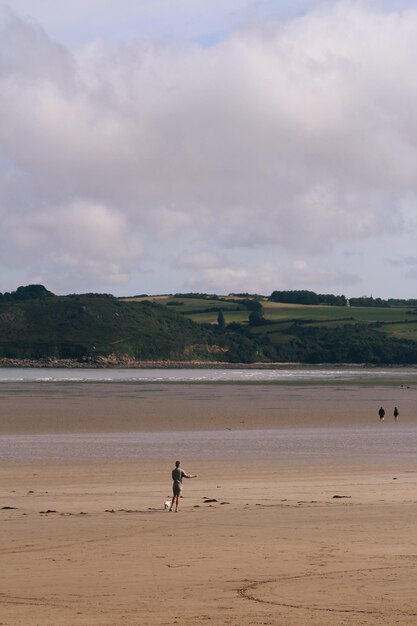 Photo a view of the beach at low tide with a woman walking its dog in the foreground