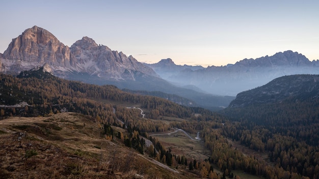 View on beautiful alpine valley during autumn sunrise with fog and golden larches dolomites italy