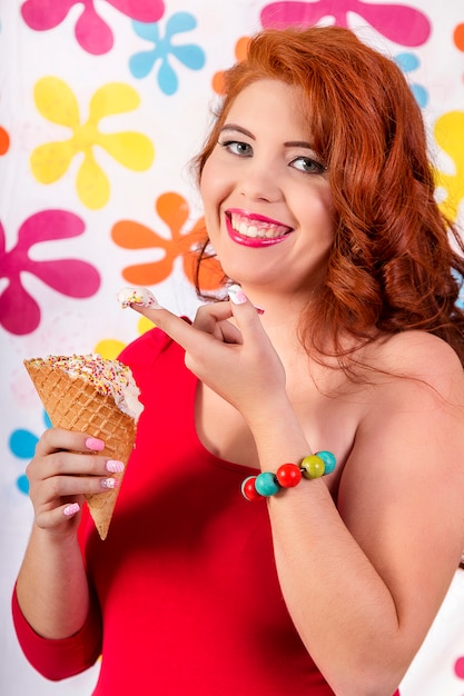 View of a beautiful redhead girl wearing colorful clothing holding an ice cream.